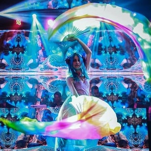 Peut inclure: Une femme en robe rose se produit avec des &eacute;ventails en tissu iris&eacute;s dans un spectacle de lumi&egrave;re bleu et vert. L'arri&egrave;re-plan est un motif en miroir de lumi&egrave;res bleues et vertes tourbillonnantes.