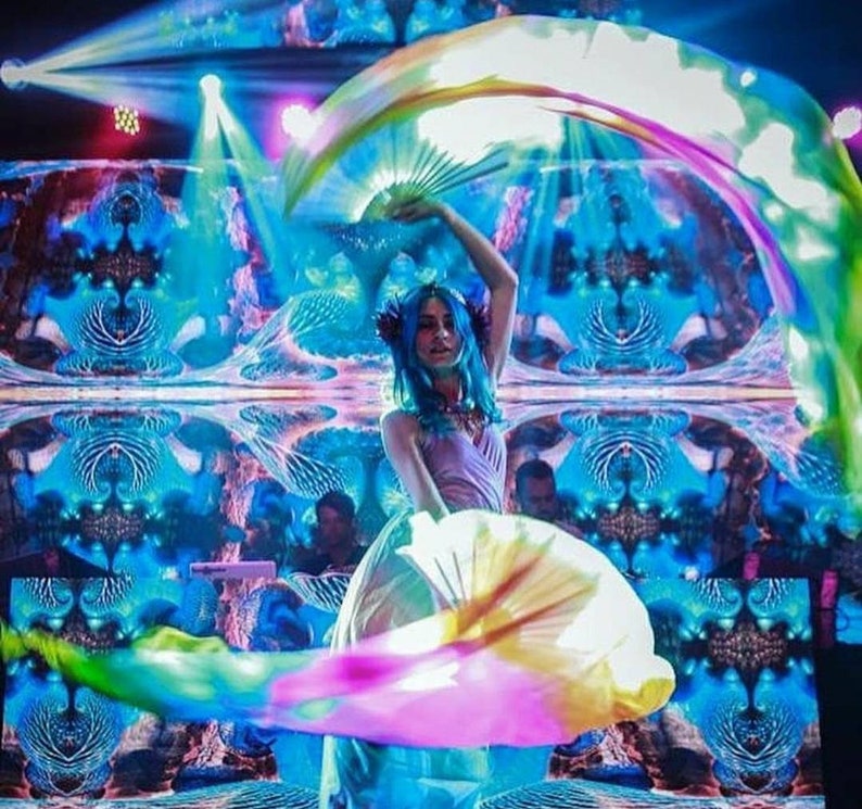 Peut inclure: Une femme en robe rose se produit avec des &eacute;ventails en tissu iris&eacute;s dans un spectacle de lumi&egrave;re bleu et vert. L'arri&egrave;re-plan est un motif en miroir de lumi&egrave;res bleues et vertes tourbillonnantes.