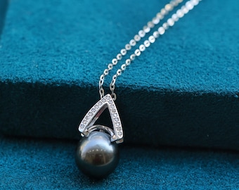 May include: A silver necklace with a black pearl pendant. The pendant is surrounded by a triangle-shaped frame with small clear stones.