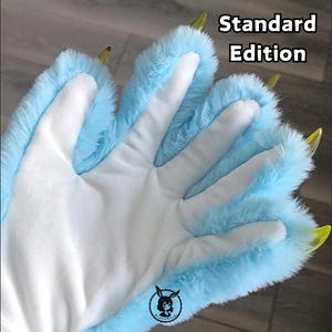 Pu&ograve; includere: Un paio di zampe di mano in pelliccia blu chiaro con artigli gialli. Le zampe sono progettate per assomigliare a zampe di animali. Il testo "Standard Edition" &egrave; visibile nell'immagine.
