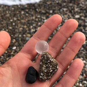 a hand holding a rock and a small plastic object