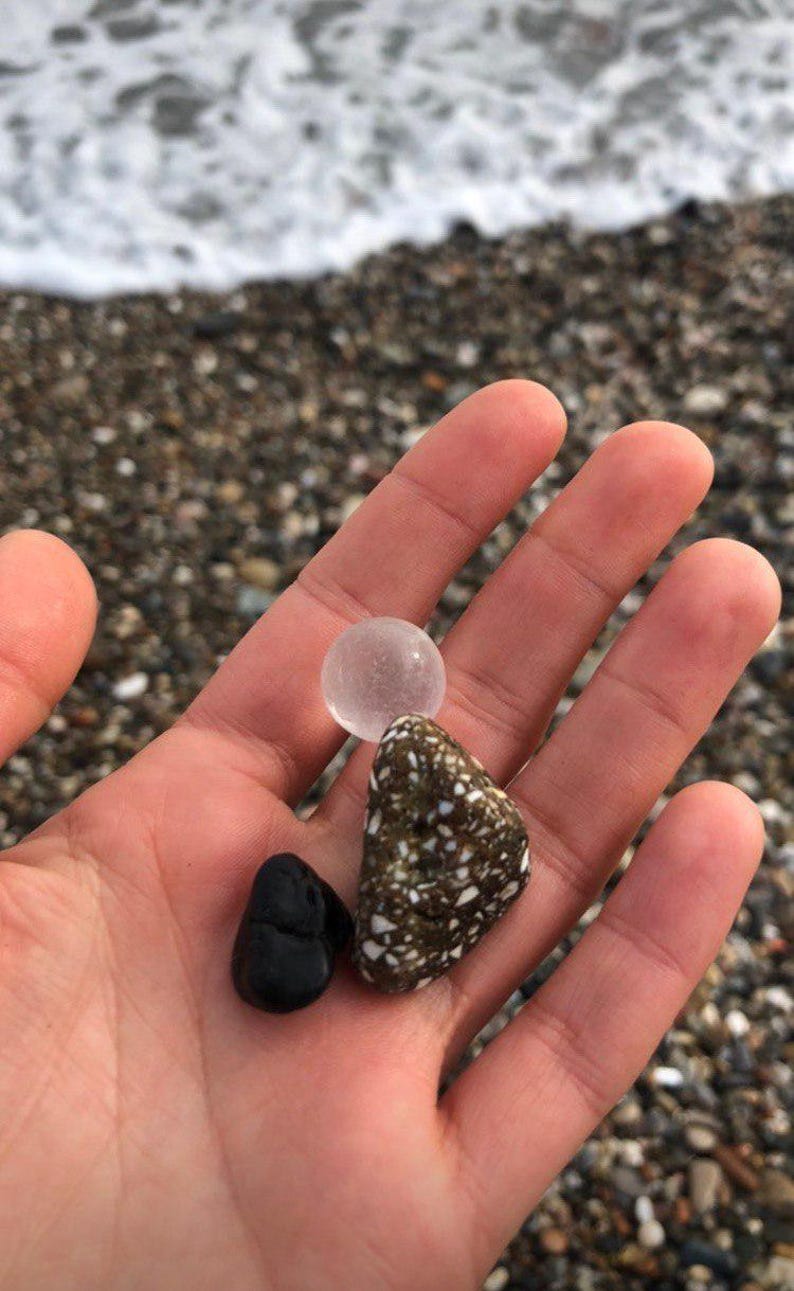 a hand holding a rock and a small plastic object