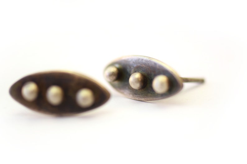 Abstract leaf stud earrings made with sterling silver. Three polished silver spheres soldered on top of the dark patina leaf shape. Perfect for everyday wear. On a white background.