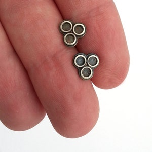 May include: A pair of silver earrings with a clover design. Each earring has three circles in the shape of a clover.