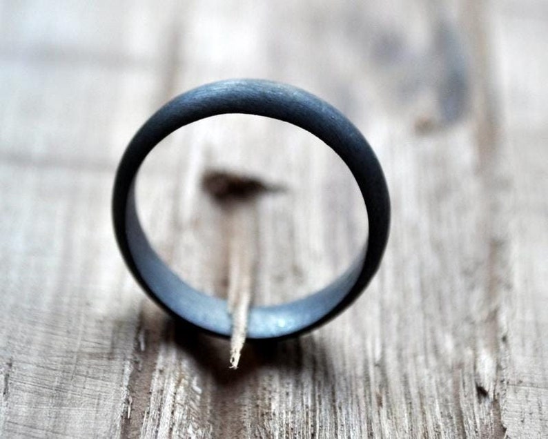 May include: A black ring with a smooth, matte finish. The ring is made of a durable material and has a simple, classic design.