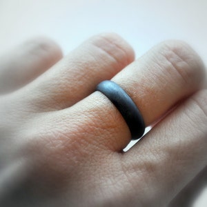 May include: A black silicone ring worn on a finger.
