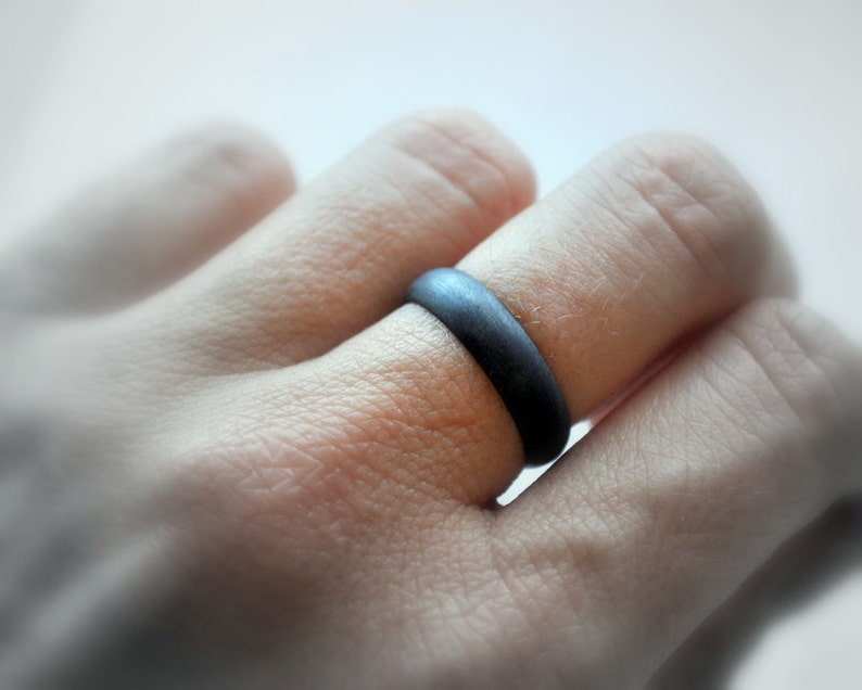 May include: A black silicone ring worn on a finger.
