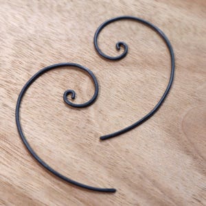 Puede incluir: Un par de pendientes de metal negro con un diseño en espiral.