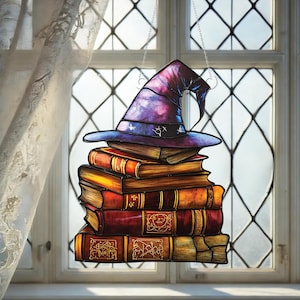Op de afbeelding: Een hangend glas-in-loodraam met een paarse tovenaarshoed bovenop een stapel oude boeken. De boeken zijn versierd met ingewikkelde ontwerpen en hebben een vintage uitstraling.