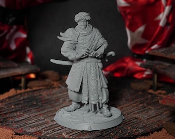 May include: A gray painted miniature figurine of a person wearing a turban and a long robe with intricate patterns. The figurine is holding a sword and is standing on a round base.