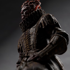 May include: A detailed statue of a regal figure with a stern expression. The figure wears an ornate, dark-colored costume with a high, ruffled collar. The statue has reddish-brown hair and a detailed, textured appearance, set against a dark gray backdrop.