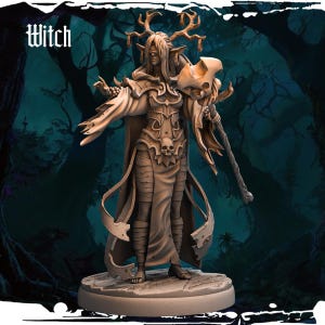 Könnte beinhalten: Eine detaillierte Miniaturfigur einer Hexe mit Geweih, die eine lange Robe trägt und einen Stab hält. Die Figur ist in hellbraun bemalt und steht auf einem runden Sockel.