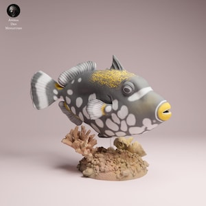 May include: A detailed sculpture of a triggerfish, with a grey body, white spots, and yellow details. The fish has a yellow mouth and is mounted above a coral and sand base. The sculpture is a miniature from Animal Des Miniatures.