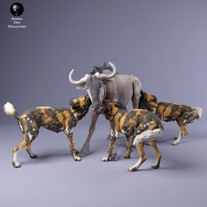 Può includere: Una collezione di statuette di animali. Uno gnu grigio chiaro è in piedi con quattro cani selvatici africani. I cani hanno un motivo maculato nero, marrone e giallo. Lo gnu ha grandi corna ricurve.