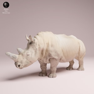 Peut inclure: Sculpture de rhinocéros blanc cassé détaillée, avec une peau texturée et une corne proéminente. La sculpture est posée sur un fond rose clair. Le logo "Animal Des Miniatures" est en haut à gauche.