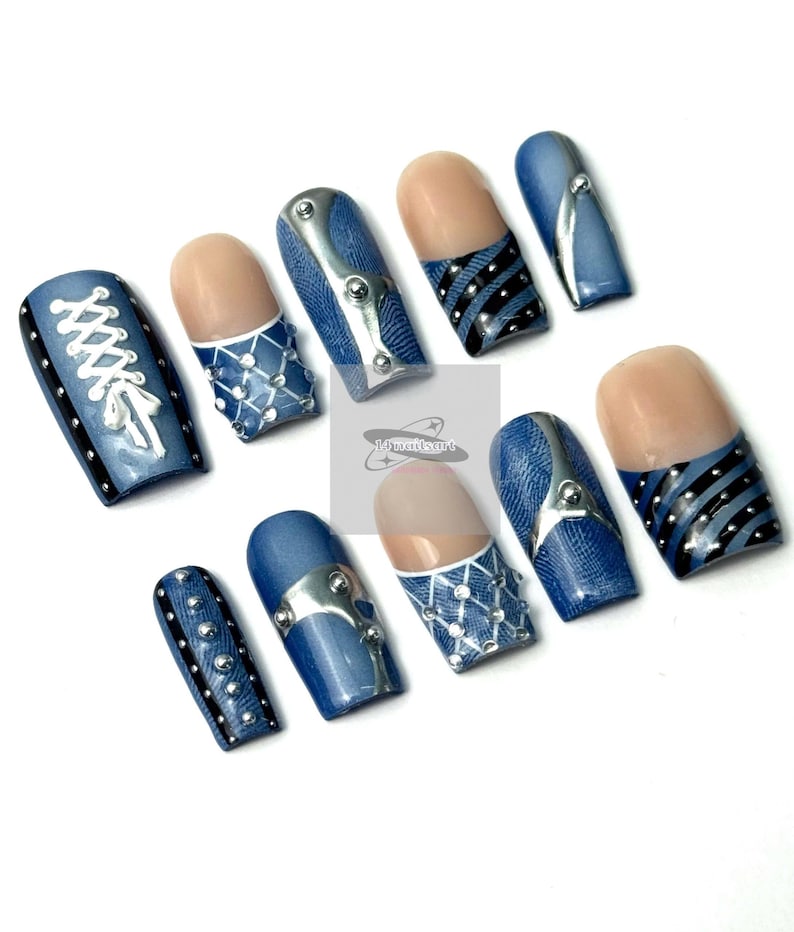 May include: A set of ten artificial nails with a denim-inspired design. The nails feature various embellishments, including silver-colored metal accents, white lace-like patterns, and black stripes. Some nails have a natural-toned base.