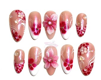 May include: Set of ten pink and white false nails with floral designs. Some nails have 3D flowers, others have painted flowers and swirls.