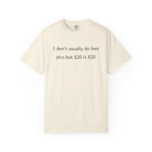 May include: Cream-colored t-shirt with the text "I don't usually do feet pics but $20 is $20" in black. The shirt has a crew neck and short sleeves. The fabric appears to be soft and comfortable.
