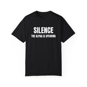 May include: Black t-shirt with white text that reads "Silence The Alpha Is Speaking."