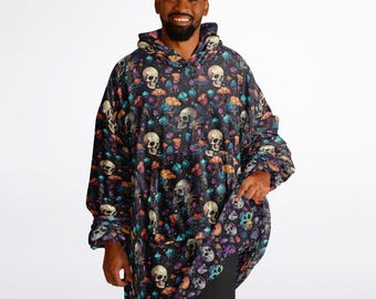 Puede incluir: Una manta negra con capucha con un patrón de calaveras y flores. La manta está hecha de tela suave y felpa y tiene un bolsillo grande en la parte delantera.