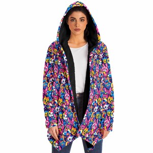 Op de afbeelding: Een zwarte hooded cardigan met een kleurrijke print van cartoondieren en regenbogen. De cardigan heeft een lange, vloeiende vorm en een zachte, pluche voering.