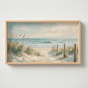 Puede incluir: Un cuadro al óleo rectangular con marco que representa una escena costera con un camino de arena hacia el océano. La obra muestra hierbas de playa, postes de madera, olas azules suaves y un cielo pálido, todo en un marco de madera clara.