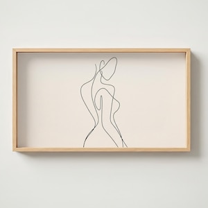 Puede incluir: Un marco rectangular de madera que contiene una impresión de color crema con un dibujo de una sola línea negra continua de una figura humana. La obra representa la silueta de un torso y una cabeza en un estilo de arte lineal fluido y abstracto.