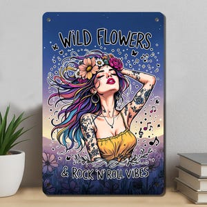 May include: Metal sign with a woman with colorful hair and floral crown. The sign reads "WILD FLOWERS & ROCK 'N' ROLL VIBES" in white text. The woman has tattoos and is wearing a yellow top. Butterflies and musical notes are scattered around the image.