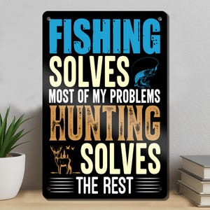 May include: A rectangular black metal sign featuring the text FISHING SOLVES MOST OF MY PROBLEMS HUNTING SOLVES THE REST. The design includes a blue fish graphic, a tan deer silhouette, and four corner holes for mounting on a wall or flat surface.