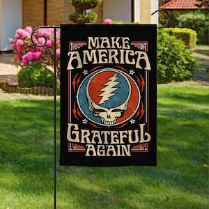 May include: Black garden flag with the text "MAKE AMERICA GRATEFUL AGAIN" in a vintage style. The flag features a skull with a lightning bolt design in a red, blue, and orange circle.