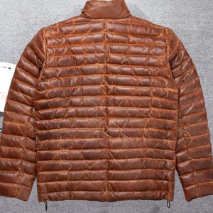 May include: A brown leather quilted jacket with a stand-up collar and zip closure.