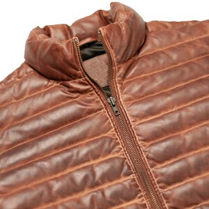 May include: A brown leather quilted jacket with a zip fastening. The jacket has a stand-up collar and a slightly distressed look.