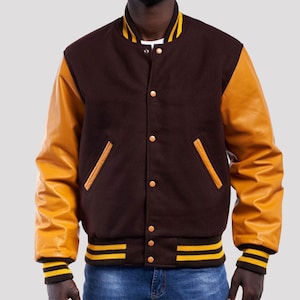May include: A brown wool varsity jacket with yellow leather sleeves and yellow and brown striped trim. The jacket has a button closure and two pockets.