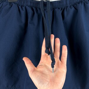 Puede incluir: Pantalones cortos deportivos azul marino con una raya blanca en el lateral y un cord&oacute;n. El logotipo de Nike es visible. Los pantalones cortos est&aacute;n hechos de un material ligero.