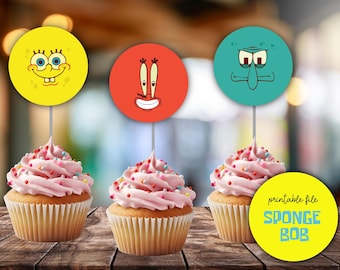 May include: Three pink cupcakes with colorful sprinkles topped with round printable paper circles featuring characters from the cartoon Spongebob Squarepants. The circles feature Spongebob, Squidward, and Mr. Krabs. The text "printable file SPONGEBOB" is on a yellow circle.