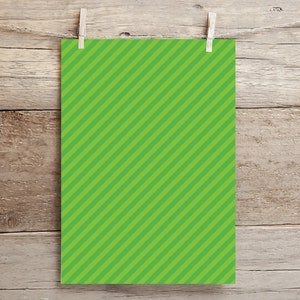 May include: A green sheet of paper with diagonal white stripes hanging on a wooden background.