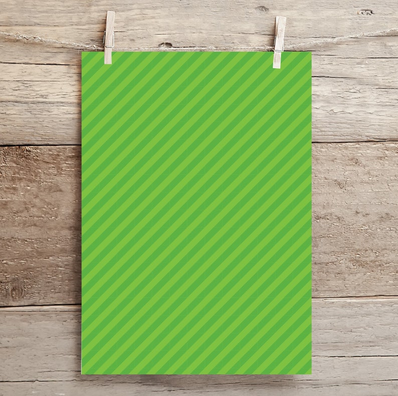 May include: A green sheet of paper with diagonal white stripes hanging on a wooden background.