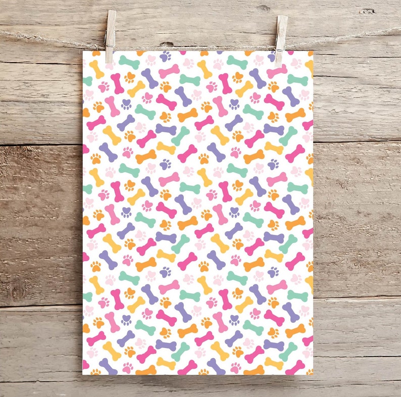 May include: A white background with a repeating pattern of colorful dog bones and paw prints. The bones are in shades of orange, pink, purple, and green. The paw prints are orange.