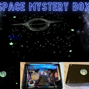 May include: A black box with the text "SPACE MYSTERY BOX" in neon blue. The box is decorated with a moon and stars. Inside the box are various space-themed items. The background features a black hole and a starry night sky.