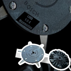 Peut inclure: Gros plan sur des pièces de machine noires et grises. L'image présente un composant circulaire avec le texte "BOSCH" et une étiquette indiquant "LUBA 1-2-X Mammotion". D'autres composants sont visibles, dont une lame circulaire avec des lames métalliques.