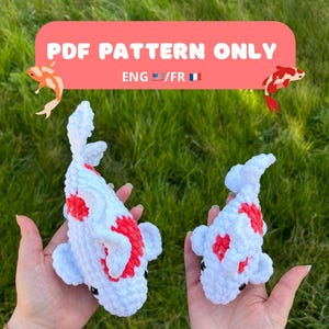 Puede incluir: Dos juguetes amigurumi de peces koi tejidos a crochet, uno blanco con marcas rojas y otro blanco con marcas rosas. Los juguetes están en las manos de una persona. El fondo es un césped verde. El texto "PDF PATTERN ONLY ENG/FR" se muestra en una pancarta rosa.