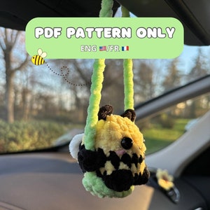 Peut inclure: Une abeille en crochet verte et jaune suspendue à un rétroviseur dans une voiture. L'abeille a des yeux noirs et une bande noire. Le texte "PDF PATTERN ONLY ENG /FR" est sur un rectangle vert au-dessus de l'abeille.