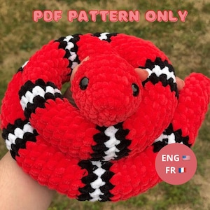 Puede incluir: Un juguete de peluche de serpiente roja, negra y blanca enrollada, con ojos negros. El texto "PDF PATTERN ONLY" está en la parte superior de la imagen. Un círculo rojo con el texto "ENG FR" y las banderas estadounidense y francesa está en la esquina inferior derecha.
