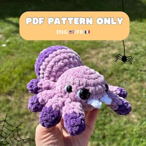Peut inclure: Une araignée crochetée violette et lavande avec des yeux noirs et des crocs blancs. L'araignée est faite de fil doux et moelleux. L'image comprend le texte "PDF PATTERN ONLY" et "ENG / FR".