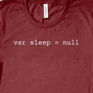 Op de afbeelding: Een maroon t-shirt met de tekst "var sleep = null" in wit gedrukt.