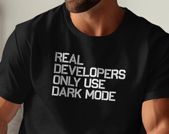 May include: Black t-shirt with white text that reads "REAL DEVELOPERS ONLY USE DARK MODE".