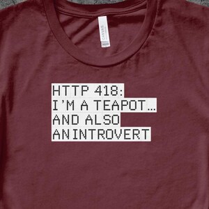 Op de afbeelding: Een maroon t-shirt met witte tekst die "HTTP 418: I'M A TEAPOT... AND ALSO AN INTROVERT" zegt.