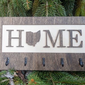May include: A wooden key holder with the word "HOME" and an outline of the state of Ohio. The key holder has five hooks.