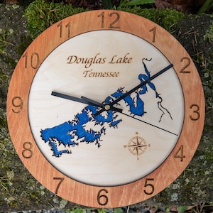 May include: A wooden clock with a blue and white map of Douglas Lake, Tennessee. The clock has a brown wooden frame and black hands.