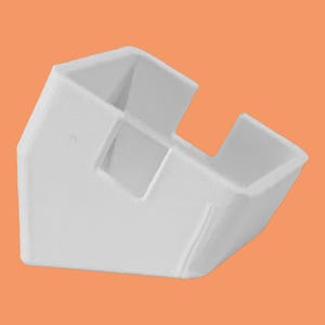 May include: A white plastic corner protector with a unique design. The protector has a rectangular shape with two open sides and a central support. It is designed to fit around a corner and protect it from damage.
